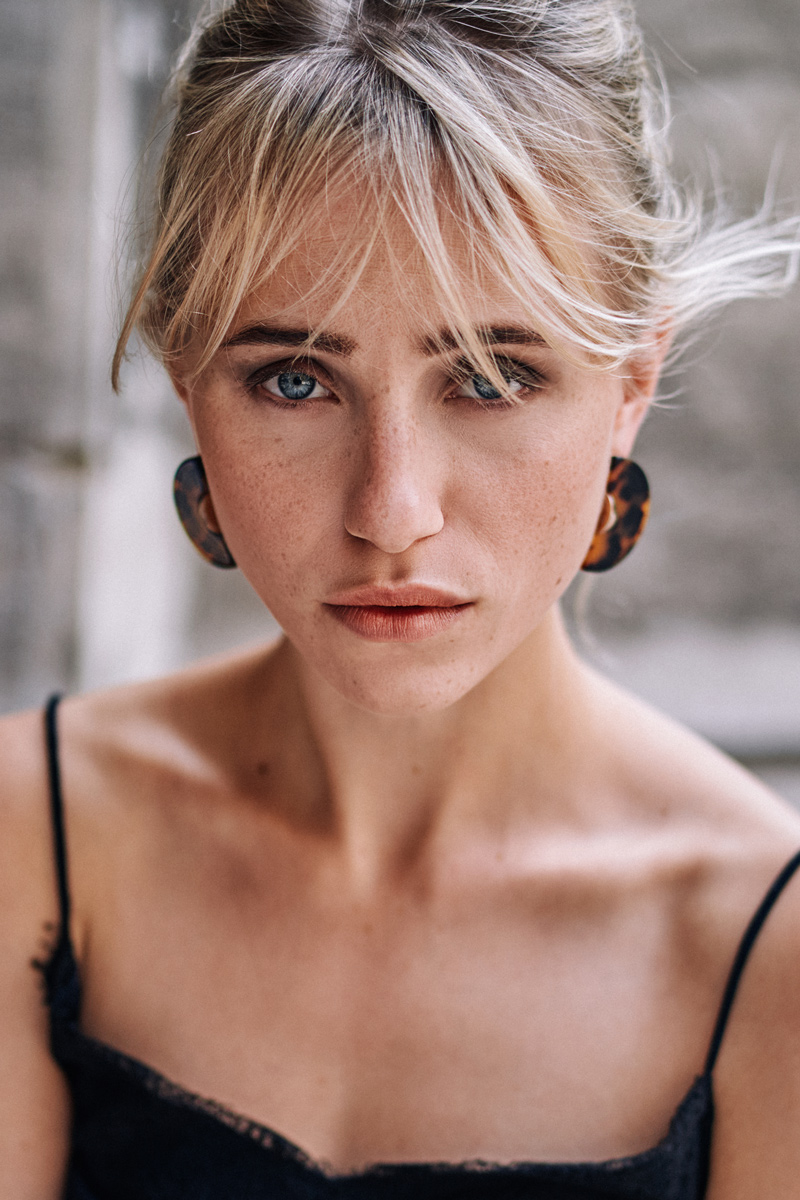 Portrait von Christa an der Universität Wien – Blonde Schönheit mit blauen Augen, gekleidet im eleganten französischen Stil, eingefangen von Johannes Schuller, Portraitfotograf aus Ried i.I.-Oberösterreich